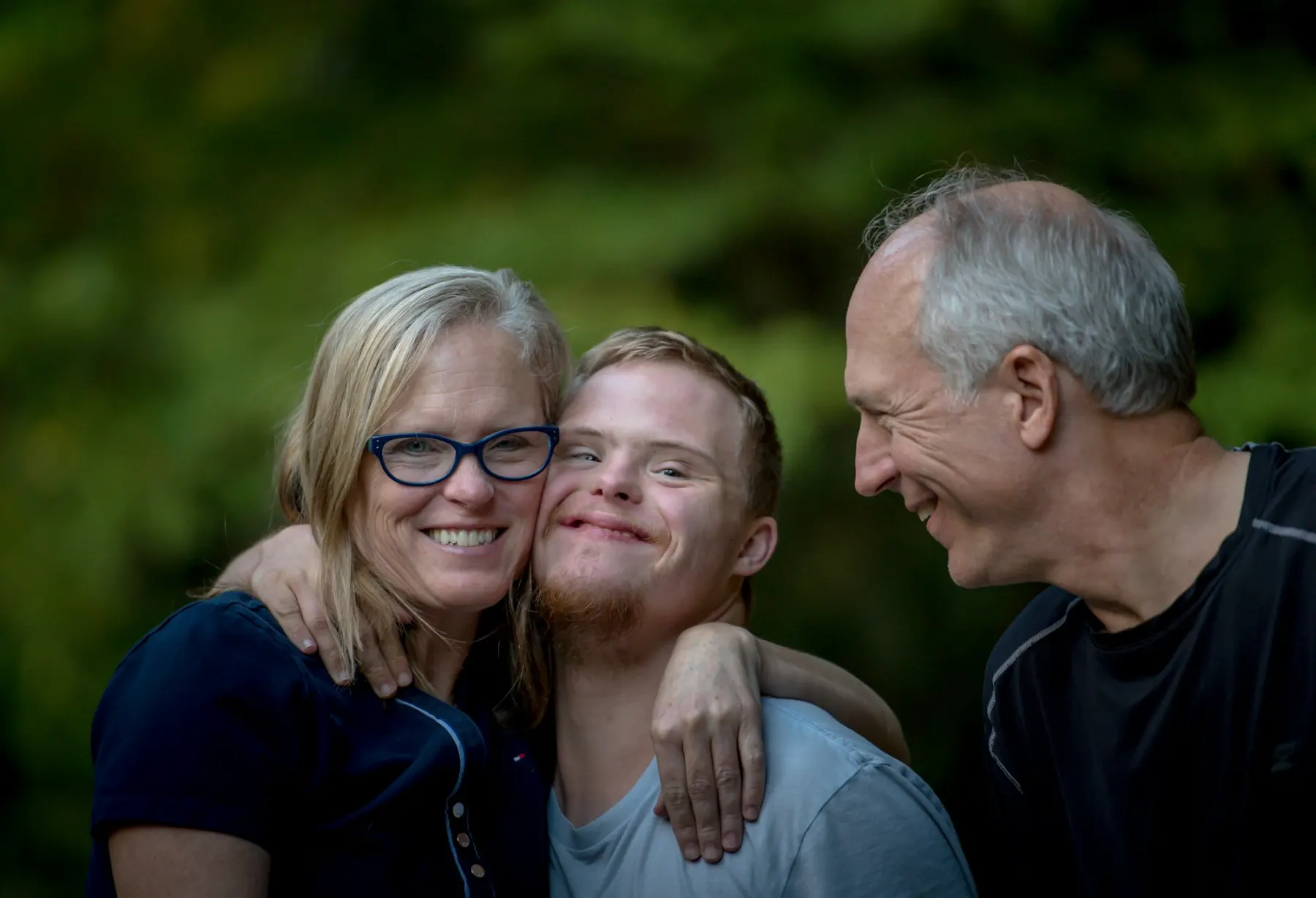 Parents smiling and embracing their adult son