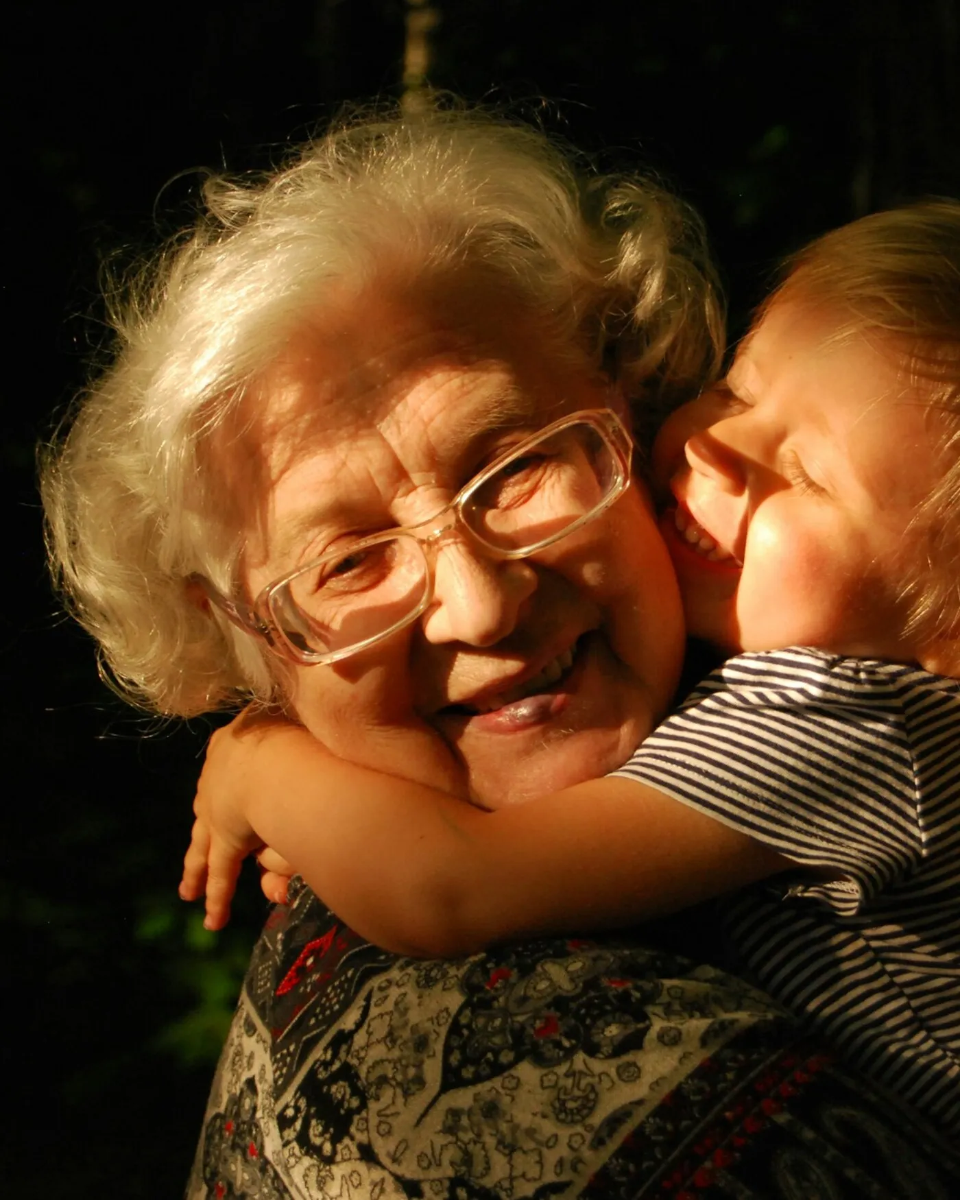 A smiling grandmother hugged by her young grandchild